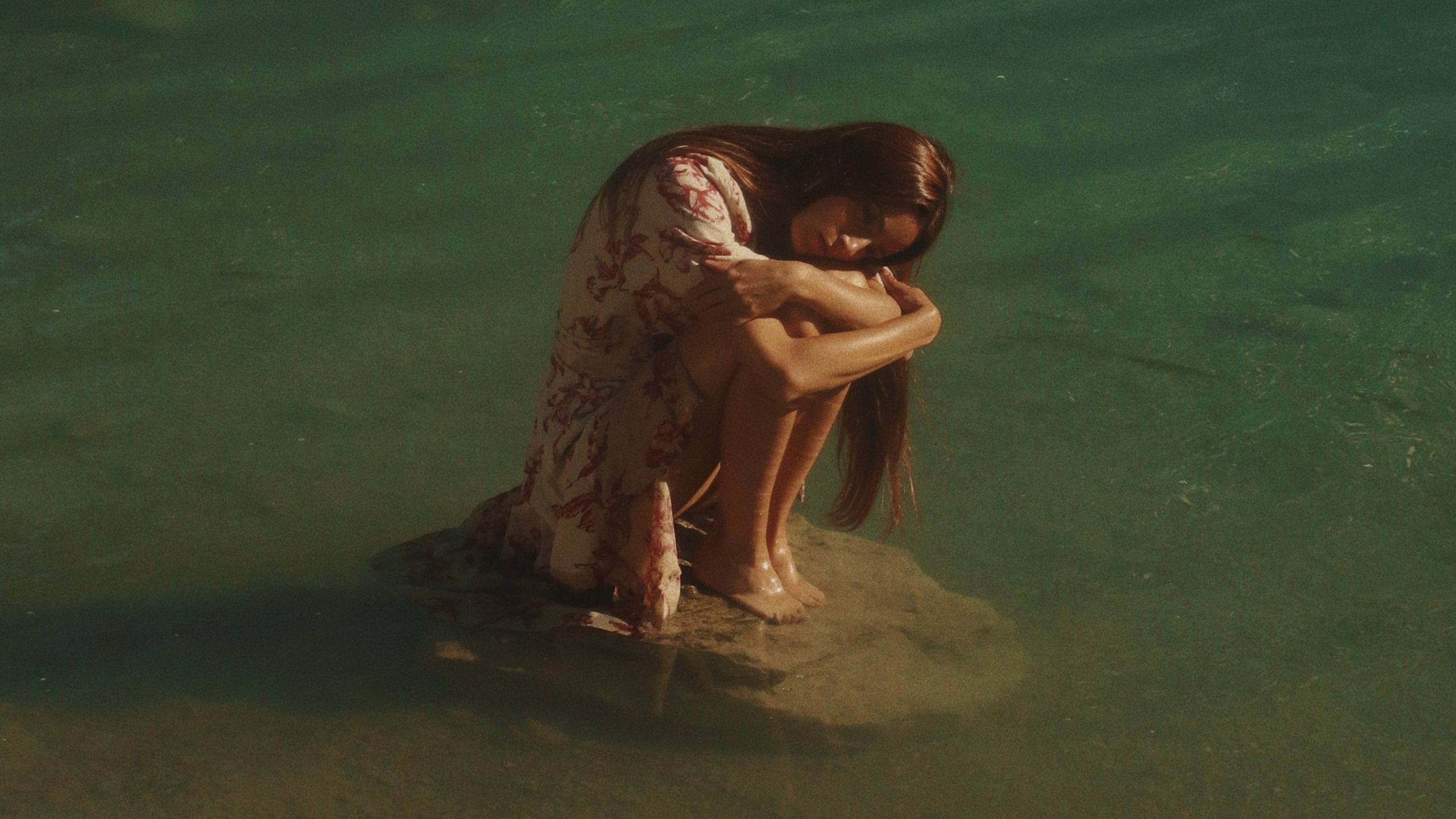 woman on sitting on a rock in lake