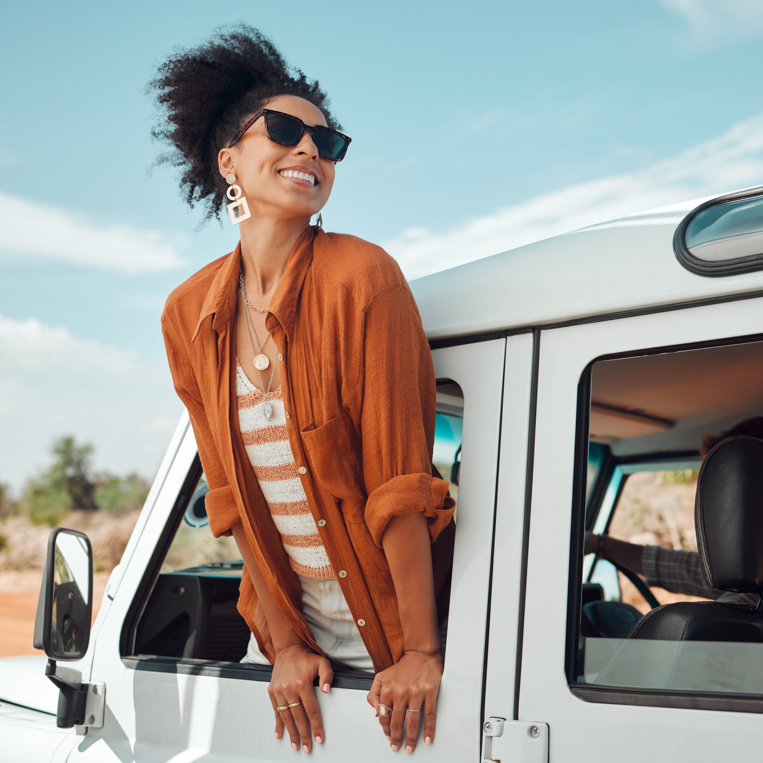 Woman hanging out a car window, smiling.